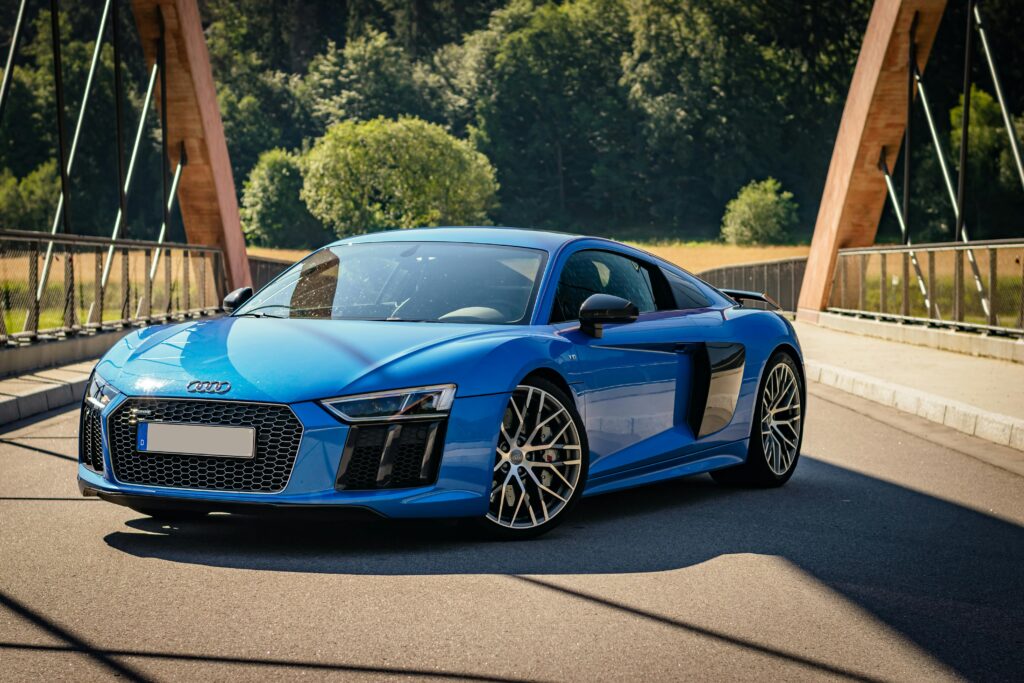 A striking blue Audi R8 sports car parked on a bridge, highlighting luxury and design.