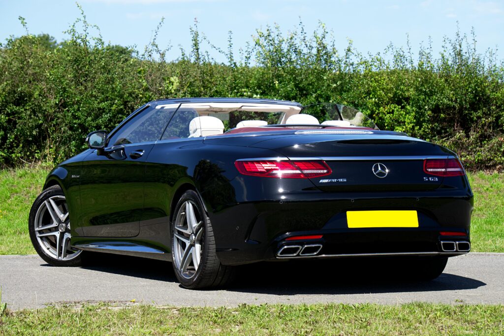 Sleek and powerful black Mercedes-Benz convertible parked on a sunny day road.