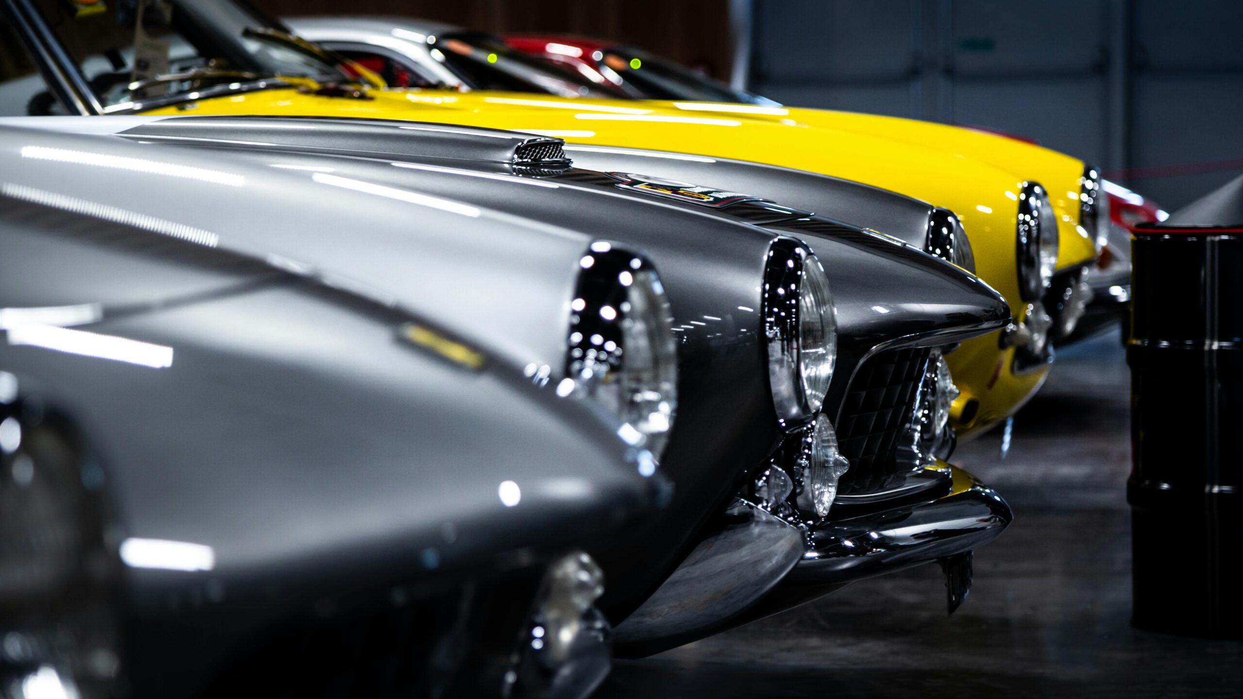 A close-up view of classic vintage cars lined up in an indoor showroom.